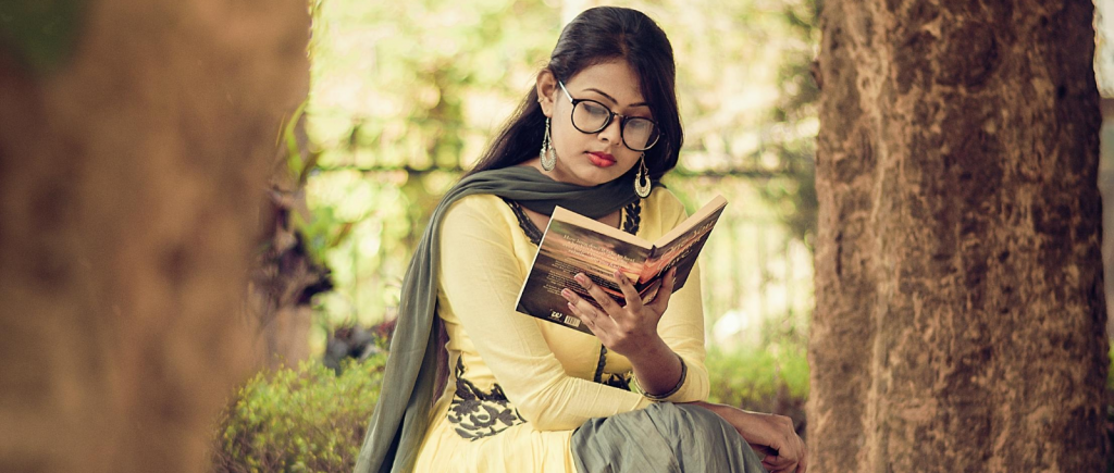 A woman sitting in a garden, reading